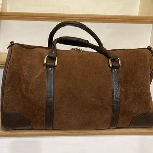 A brown suede duffel bag with leather trimming